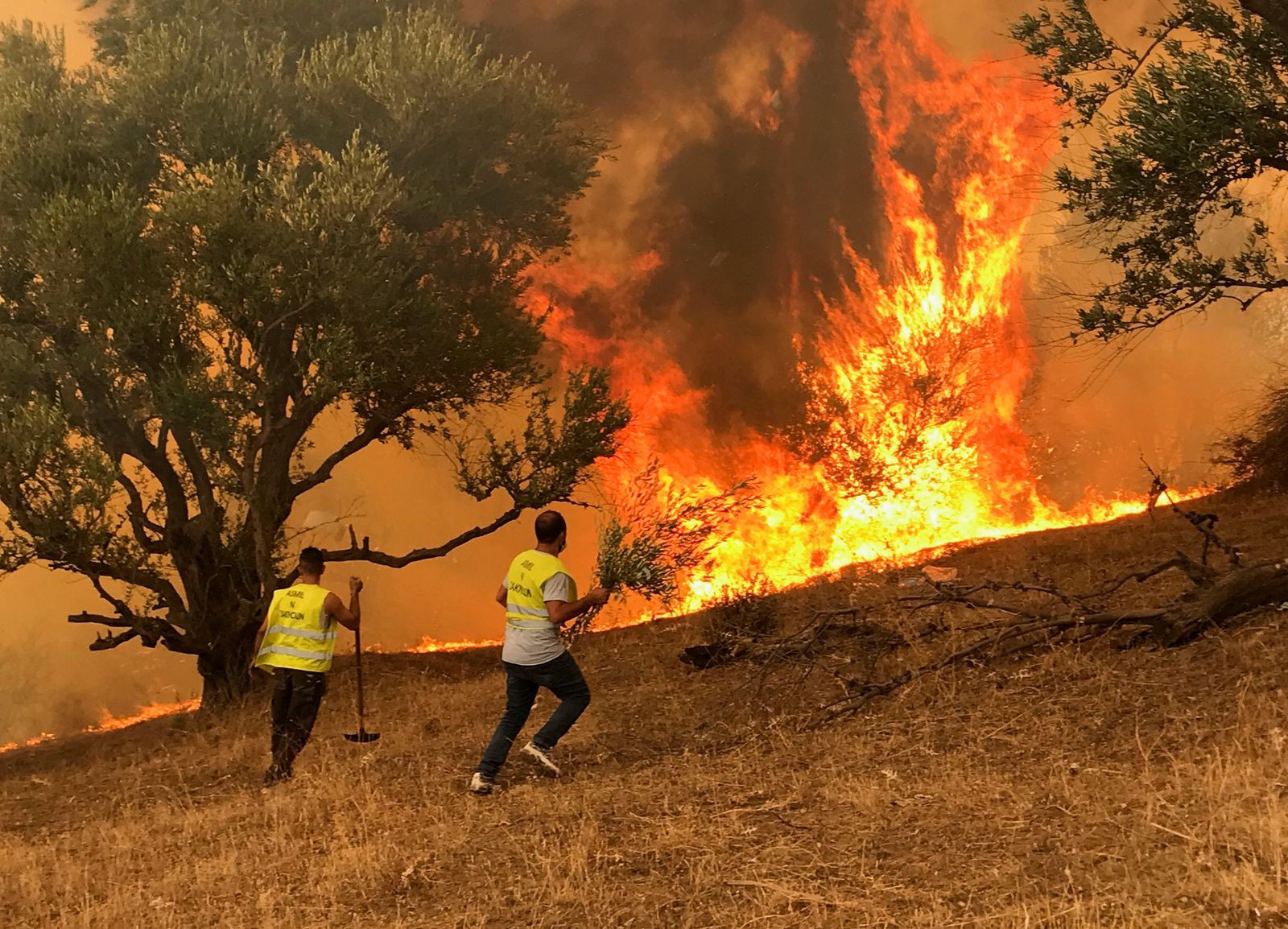 رجال يحاولون إخماد حريق في قرية إيبودرارين بمنطقة القبائل الجبلية في تيزي وزو شرق الجزائر العاصمة - 12 أغسطس 2021. - REUTERS