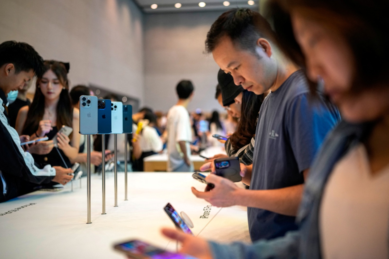 أشخاص يفصحون أجهزة آيفون 15 داخل أحد متاجر شركة أبل في شنغهاي بالصين. 22 سبتمبر 2023