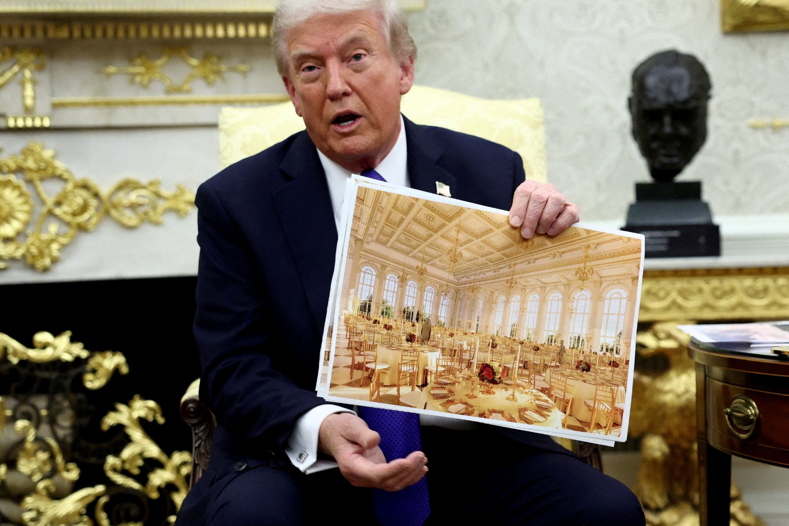 الرئيس الأميركي دونالد ترمب يحمل صورة تظهر تصميم قاعة الحفلات الجديدة في البيت الأبيض، التي يتم بناؤها. 22 أكتوبر 2025