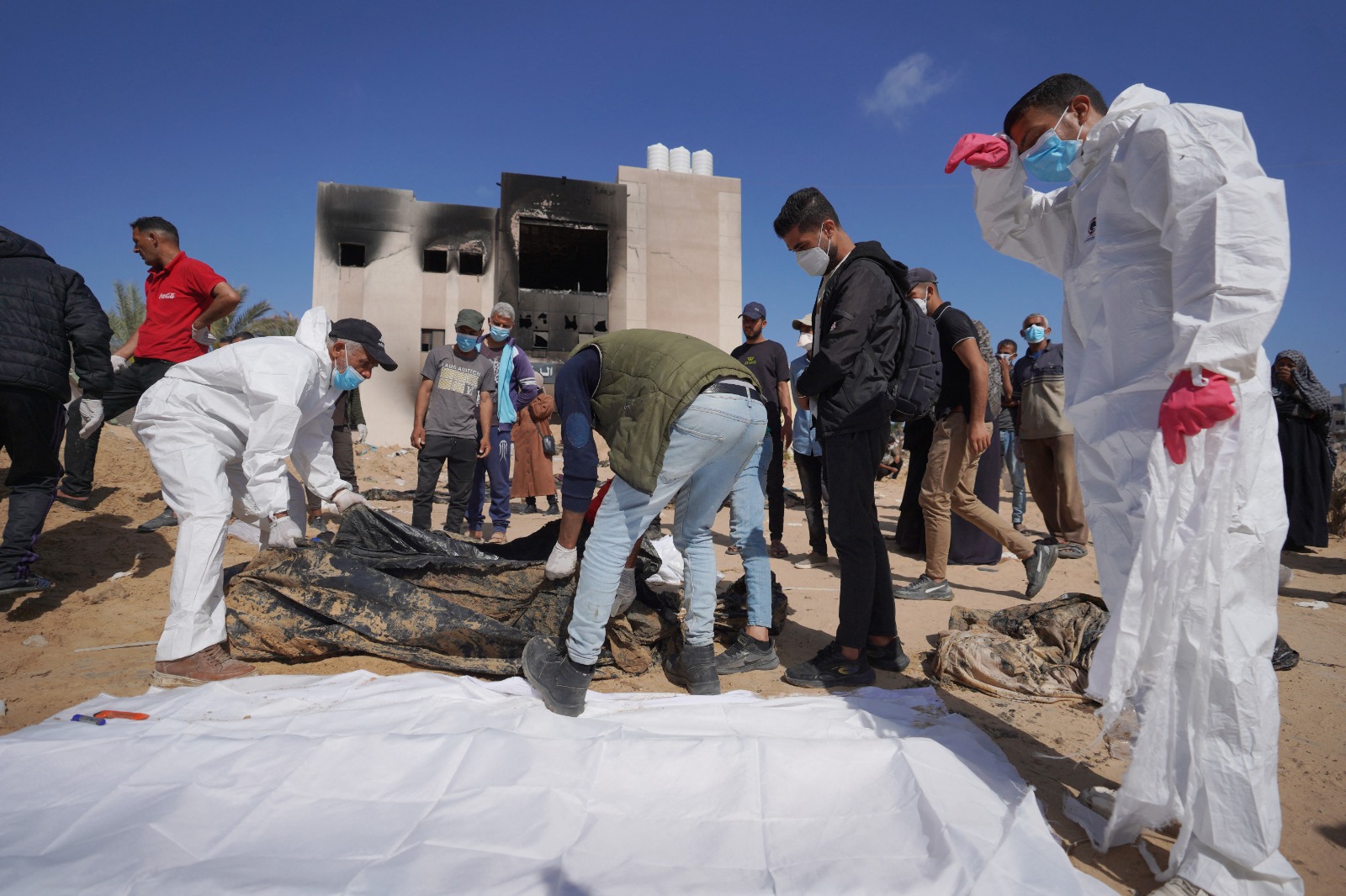 عاملون صحيون فلسطينيون يستخرجون جثثاً قتلتها القوات الإسرائيلية ودفنتها في مقابر جماعية بمجمع مستشفى ناصر في خان يونس، جنوب قطاع غزة. 21 أبريل 2024