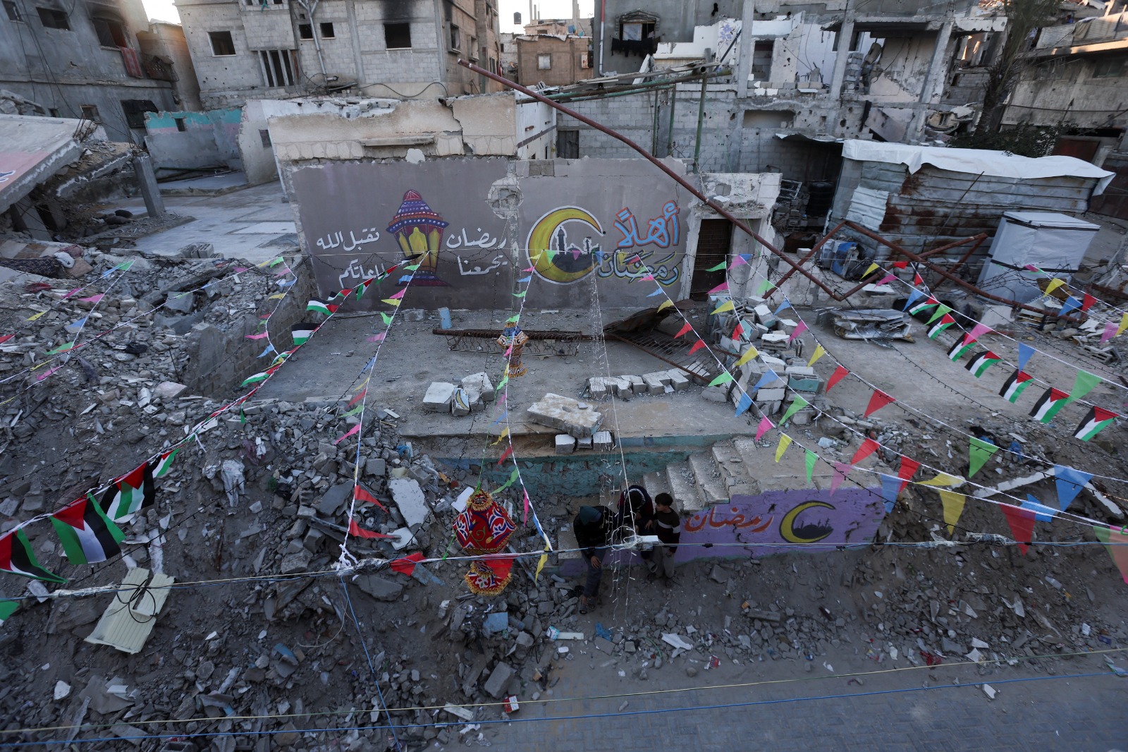 فلسطينيون يتجمعون بالقرب من كتابات الجرافيتي وأنقاض المباني في خان يونس جنوب قطاع غزة. 27 فبراير 2025