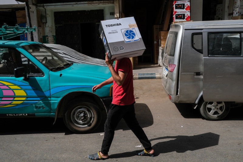 شخص يحمل مروحة جديدة خلال درجات حرارة مرتفعة في منطقة العتبة في القاهرة