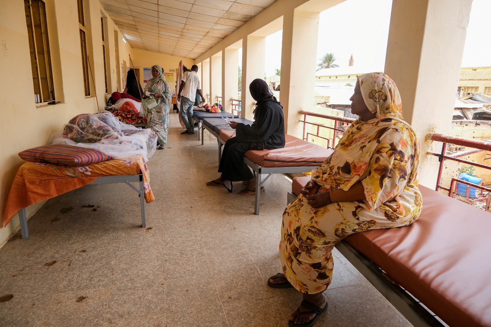 نساء سودانيات يجلسن على أسرّة لمتابعة ذويهن المصابين بحمى الضنك في مستشفى أم درمان، بينما يكافح السودان تفشي الضنك والكوليرا وسط موسم الأمطار السنوي وانهيار النظام الصحي والبنية التحتية، الخرطوم. 23 سبتمبر 2025.