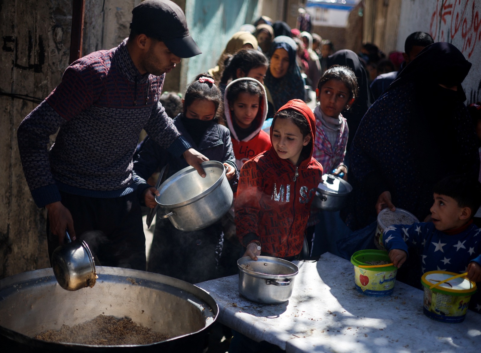 أطفال فلسطينيون ينتظرون الحصول على الطعام في رفح جنوبي قطاع غزة بينما يتواصل القصف الإسرائيلي على القطاع الذي يعاني من نقص حاد في الغذاء. 5 مارس 2024