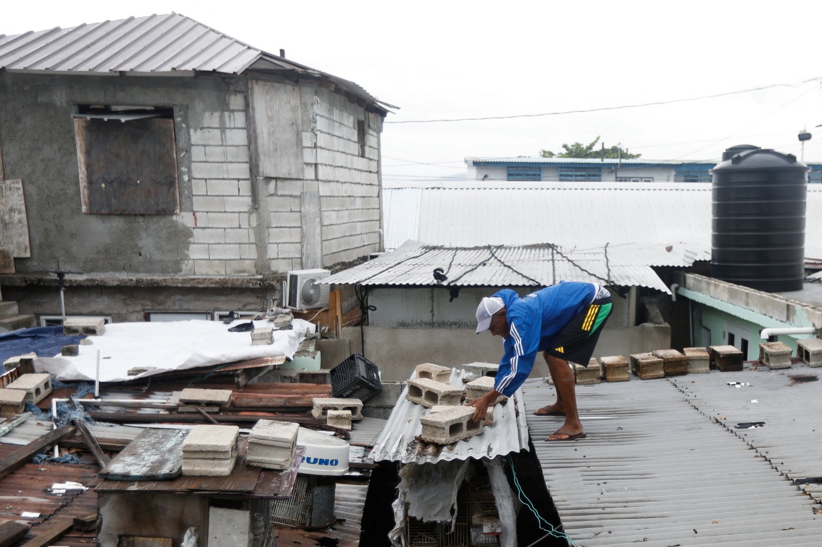 رجل يضع كتلاً خرسانية على سقف قفص الدجاج استعداداً لوصول الإعصار ميليسا، في بورت رويال، جامايكا. 26 أكتوبر 2025