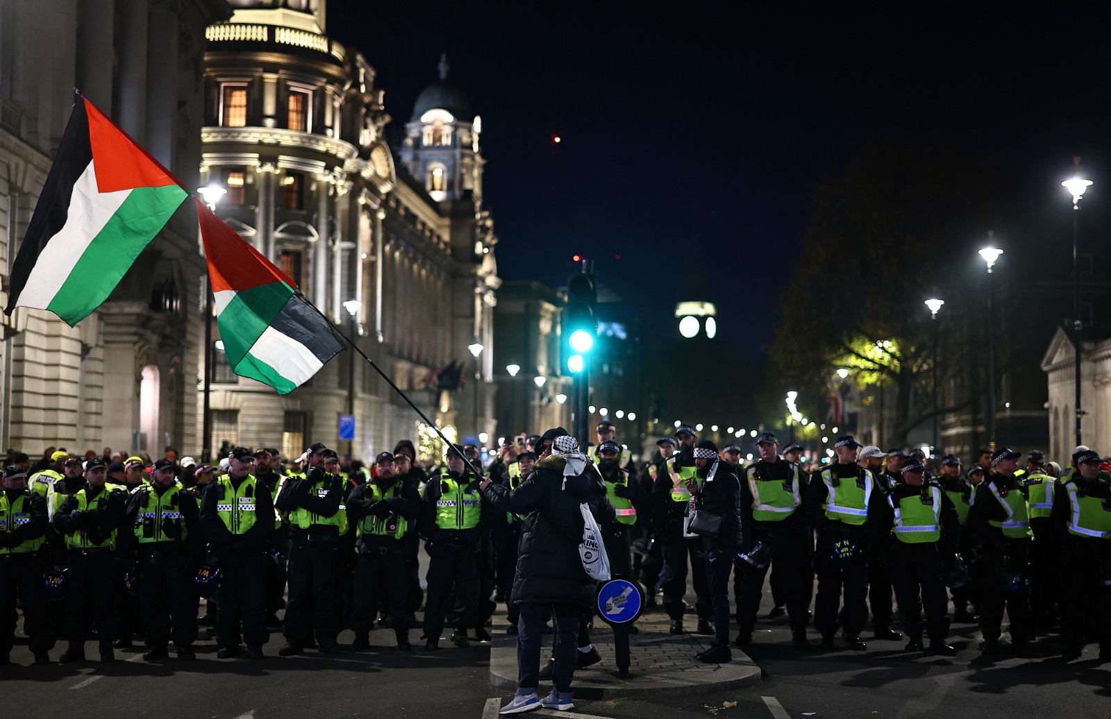 متظاهر يلوح بعلم فلسطين في مواجهة ضباط شرطة خلال “المسيرة الوطنية من أجل فلسطين” في وسط لندن، بريطانيا. 25 نوفمبر 2023