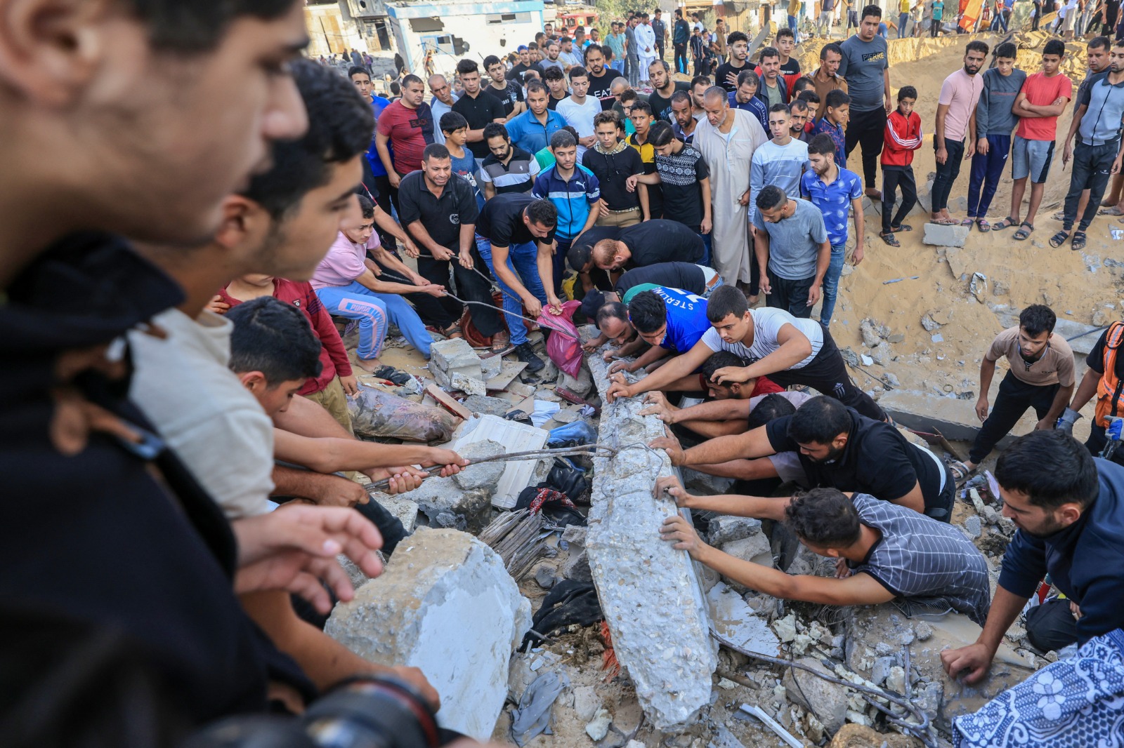 فلسطينيون يبحثون عن أحياء عالقين تحت أنقاض مبنى دمرته غارة إسرائيلية في خان يونس جنوبي قطاع غزة. 16 أكتوبر 2023