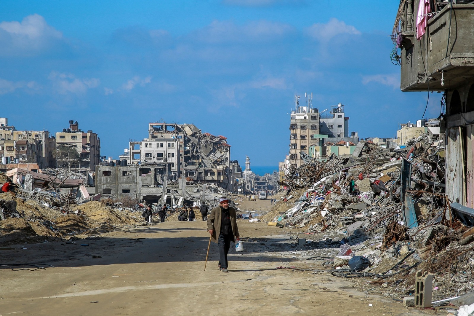 فلسطينيون يسيرون في شارع العيون بمدينة غزة وسط أنقاض المباني المدمرة، في 3 فبراير 2024 - AFP