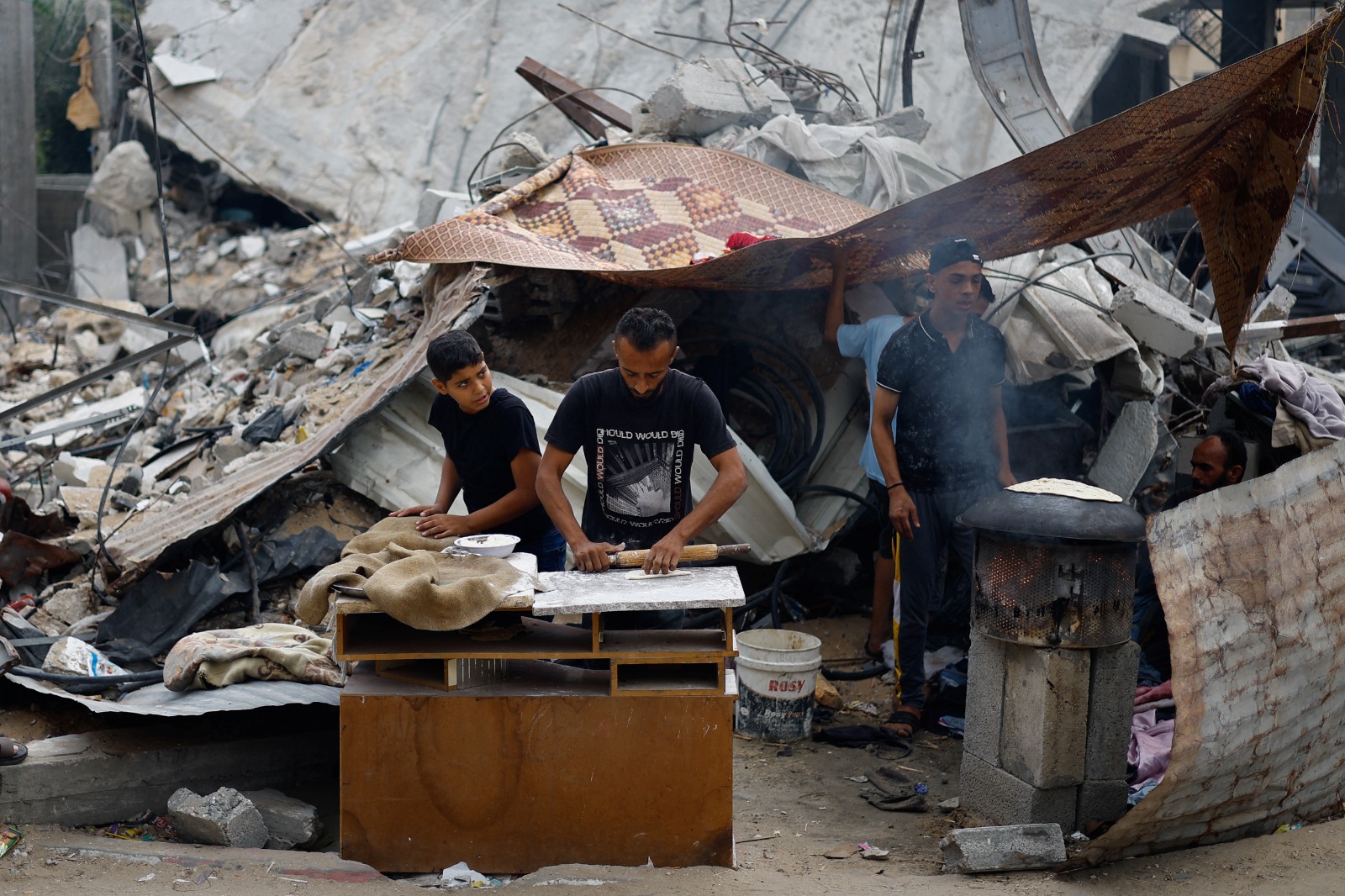 فلسطينيون يعدون الطعام بجوار المباني المدمرة، في أعقاب الضربات الإسرائيلية في خان يونس بجنوب قطاع غزة، 13 نوفمبر 2023