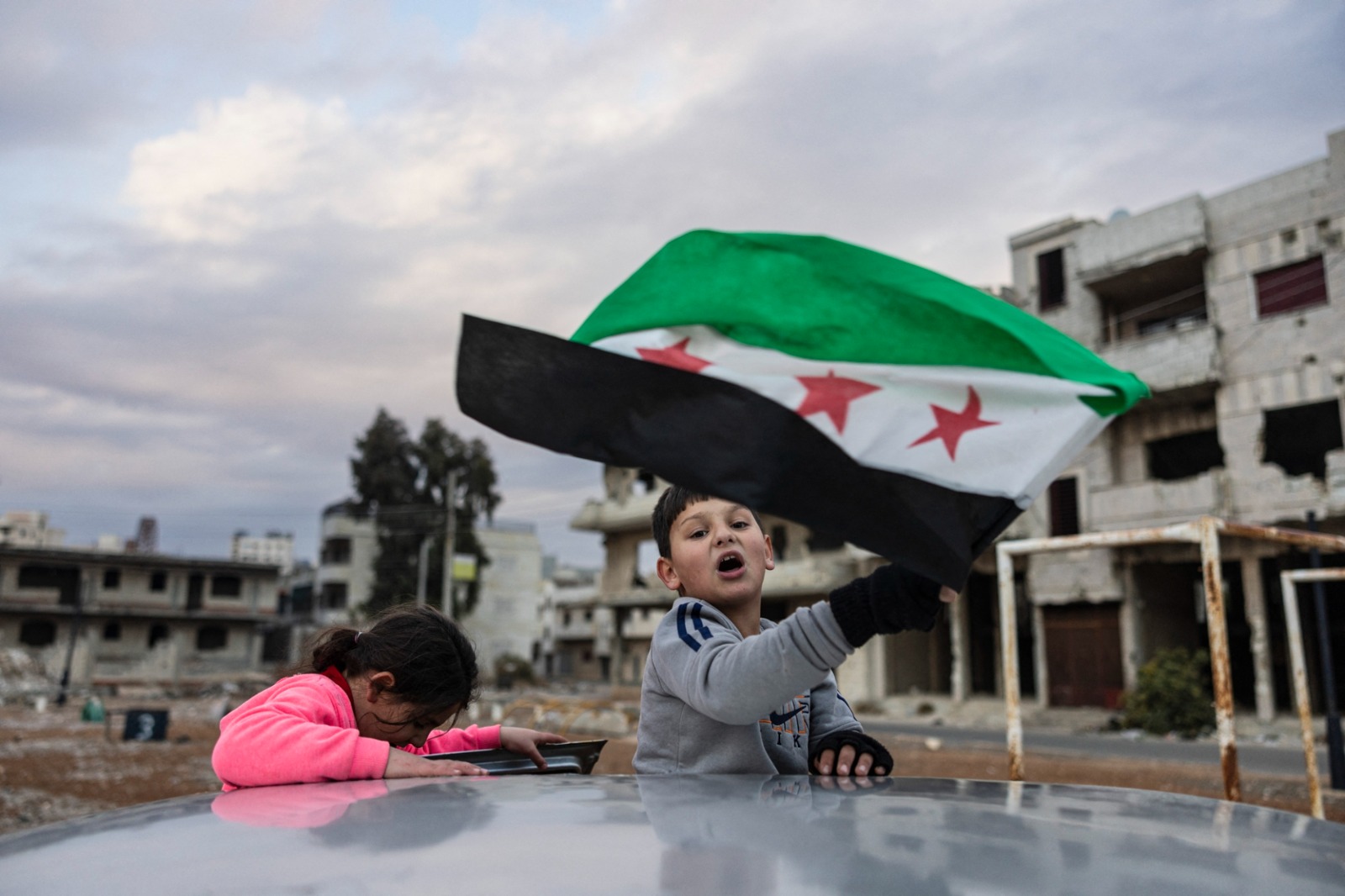 طفل سوري يلوح بعلم سوريا الجديد خلال الاحتفالات بالإطاحة بالرئيس السوري بشار الأسد في حمص، 20 ديسمبر 2024