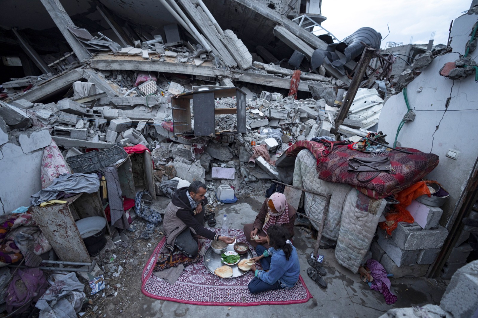 أفراد عائلة فلسطينية يتناولون إفطارهم خلال شهر رمضان أمام حطام منزلهم المدمر جراء الغارات الجوية الإسرائيلية