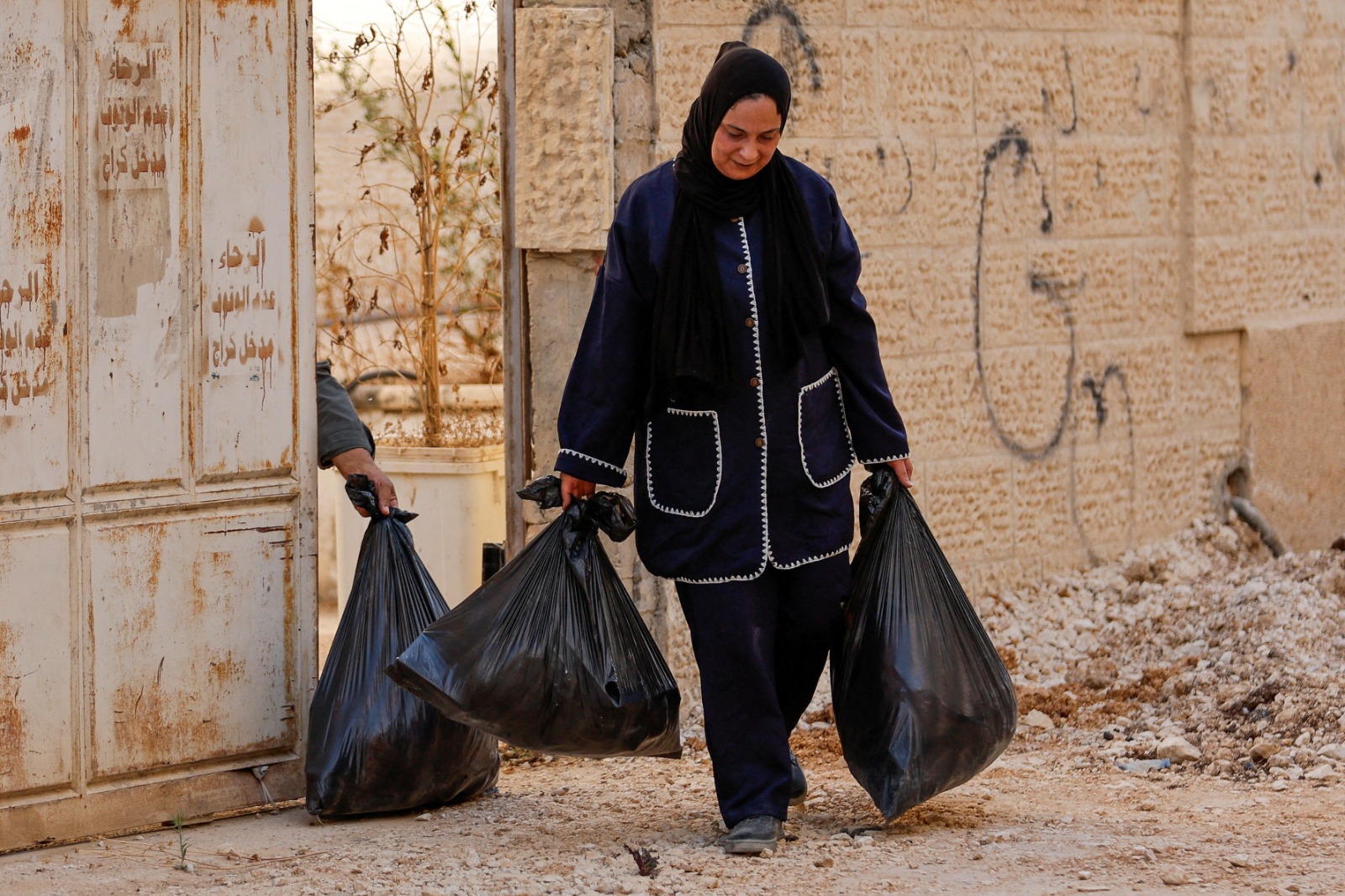 فلسطينية تحمل بعض المقتنيات في كيس بلاستيكي بعد إجبارها على الخروج من منزلها وسط عملية إسرائيلية في جنين، الضفة الغربية المحتلة، 8 يوليو 2025