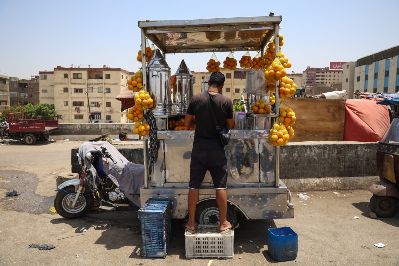 بائع عصير برتقال يقف خلال درجات حرارة مرتفعة في القاهرة