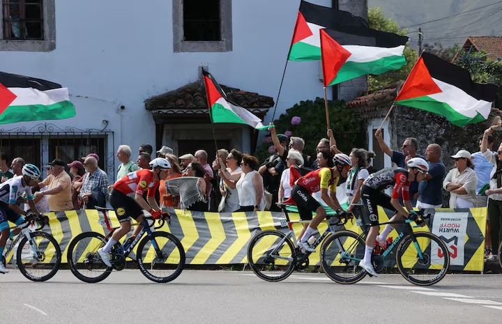 مشاركون في سباق إسبانيا للدراجات يمرون بمحتجين يرفعون أعلام فلسطين، كانتابريا، إسبانيا، 5 سبتمبر 2025