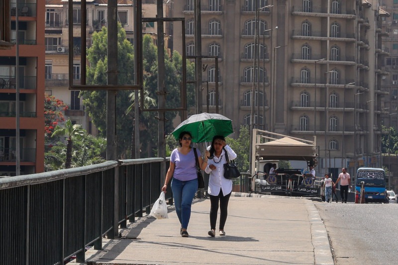 سيدتان تسيران تحت مظلة تحميهما من الطقس الحار في وسط القاهرة