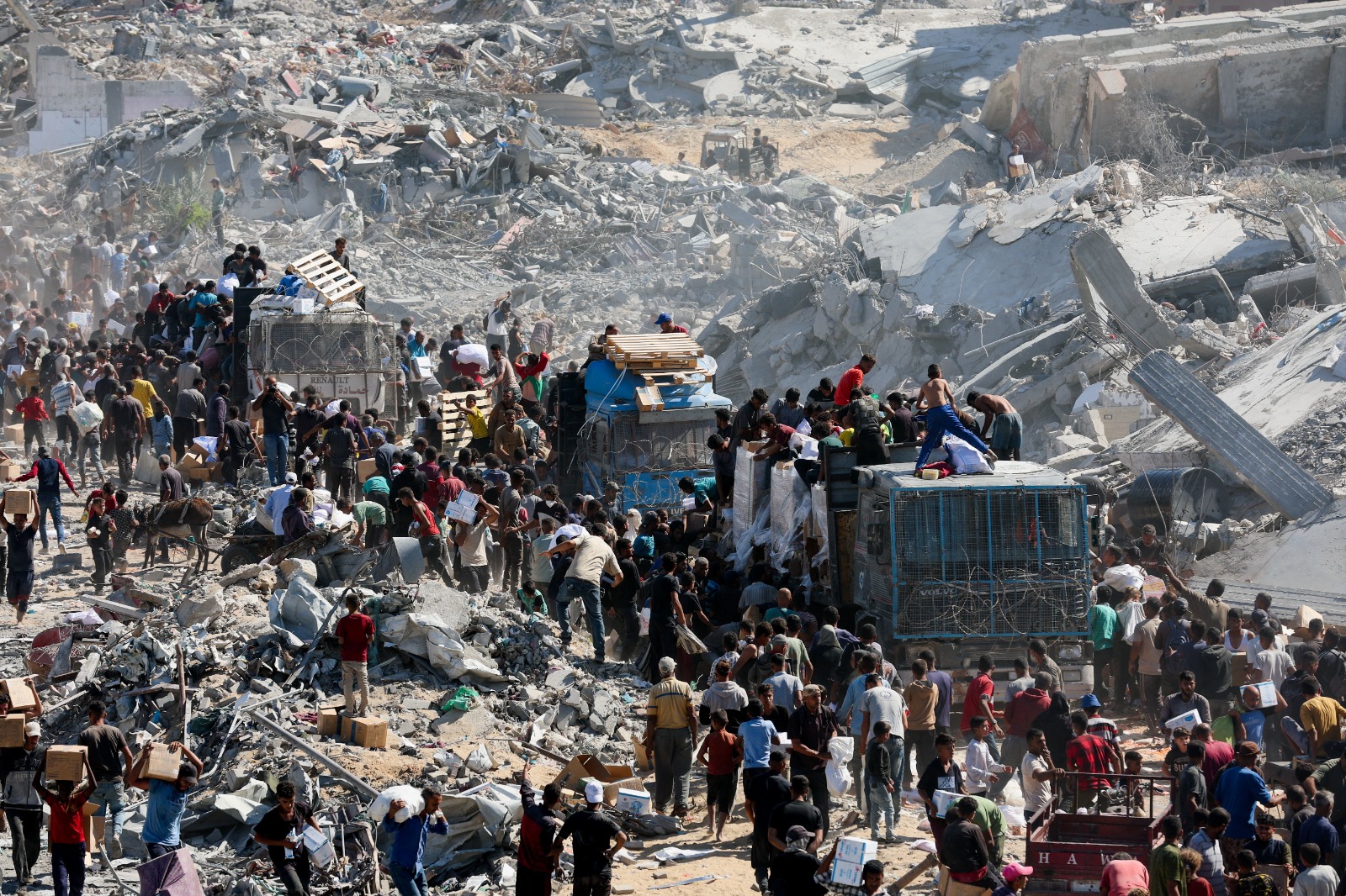 فلسطينيون يجمعون إمدادات المساعدات من الشاحنات التي دخلت غزة وسط وقف إطلاق النار بين إسرائيل وحركة حماس في خان يونس بجنوب قطاع غزة. 12 أكتوبر 2025