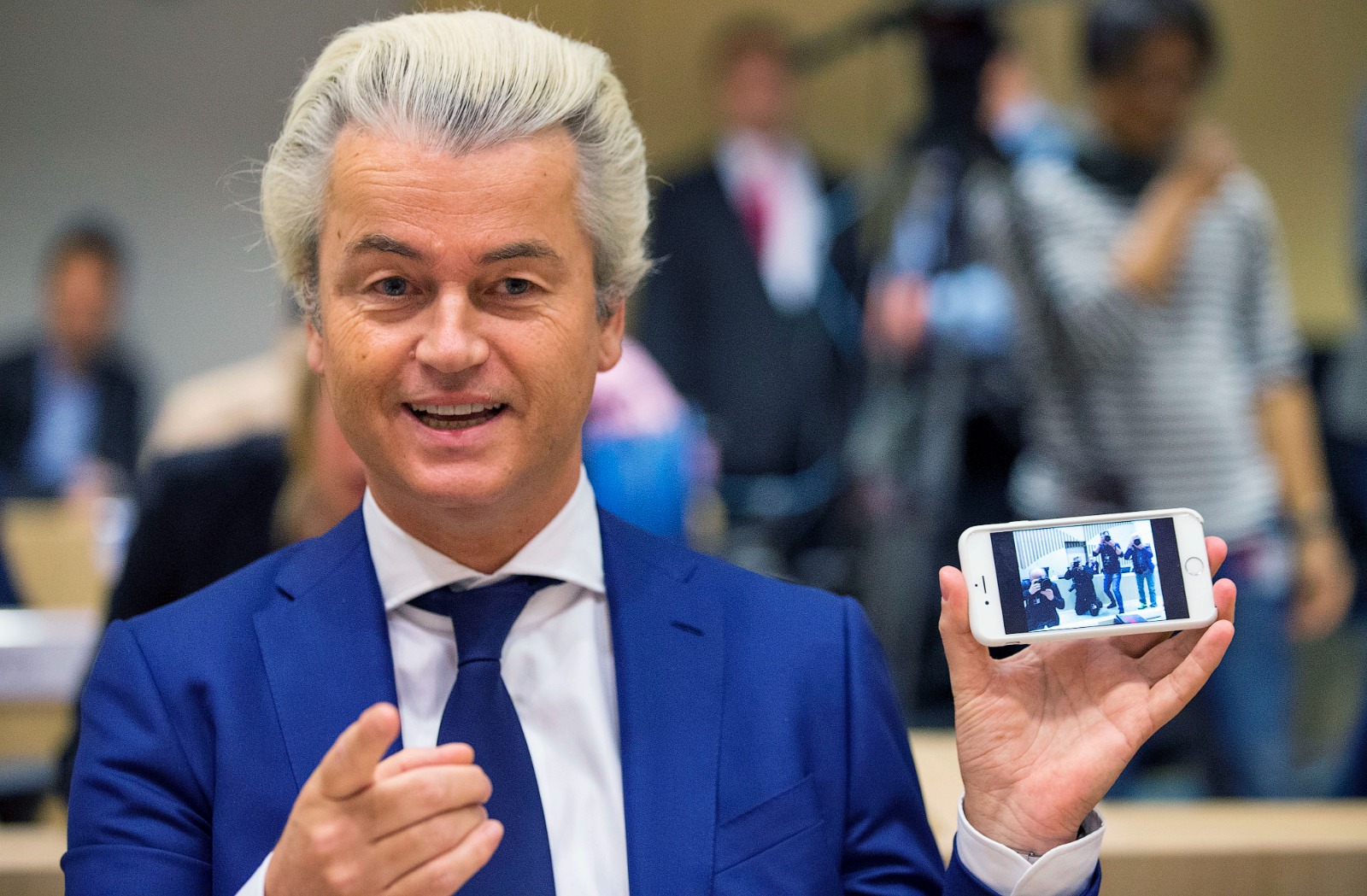 زعيم حزب الحرية الهولندي اليميني المتطرف خيرت فيلدرز يظهر صورة للمصورين الذين التقطهم بهاتفه الخلوي قبل محاكمته في قاعة المحكمة في شيفول بهولندا، 18 مارس 2016-