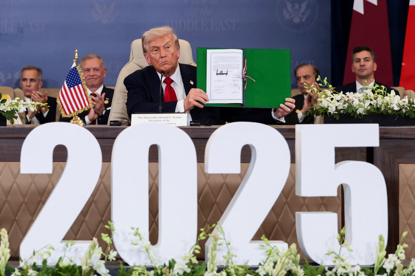 الرئيس الأميركي دونالد ترمب يحمل وثيقة السلام التي وقعها في مدينة شرم الشيخ المصرية. 13 أكتوبر 2025