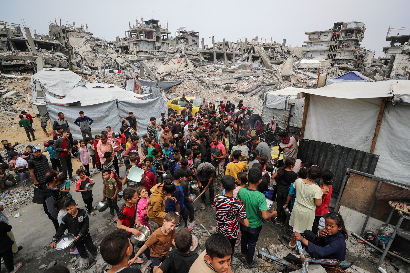 فلسطينيون ينتظرون الحصول على طعام من مطبخ خيري وسط الأنقاض في بيت لاهيا شمال قطاع غزة. 24 أبريل 2025