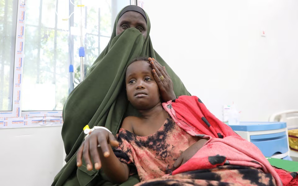 سيدة تساعد طفلة مصابة بالدفتيريا داخل جناح في مستشفى دي مارتينو العام، مقديشو، الصومال، 13 أغسطس 2025