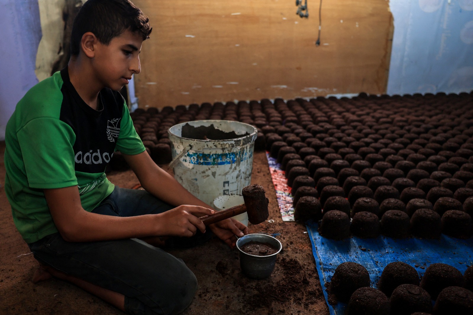 طفل فلسطيني يصنع خليطاً من مسحوق الزيتون لاستخدامه في إشعال النار في ظل نقص الوقود في قطاع غزة، 14 نوفمبر 2023.