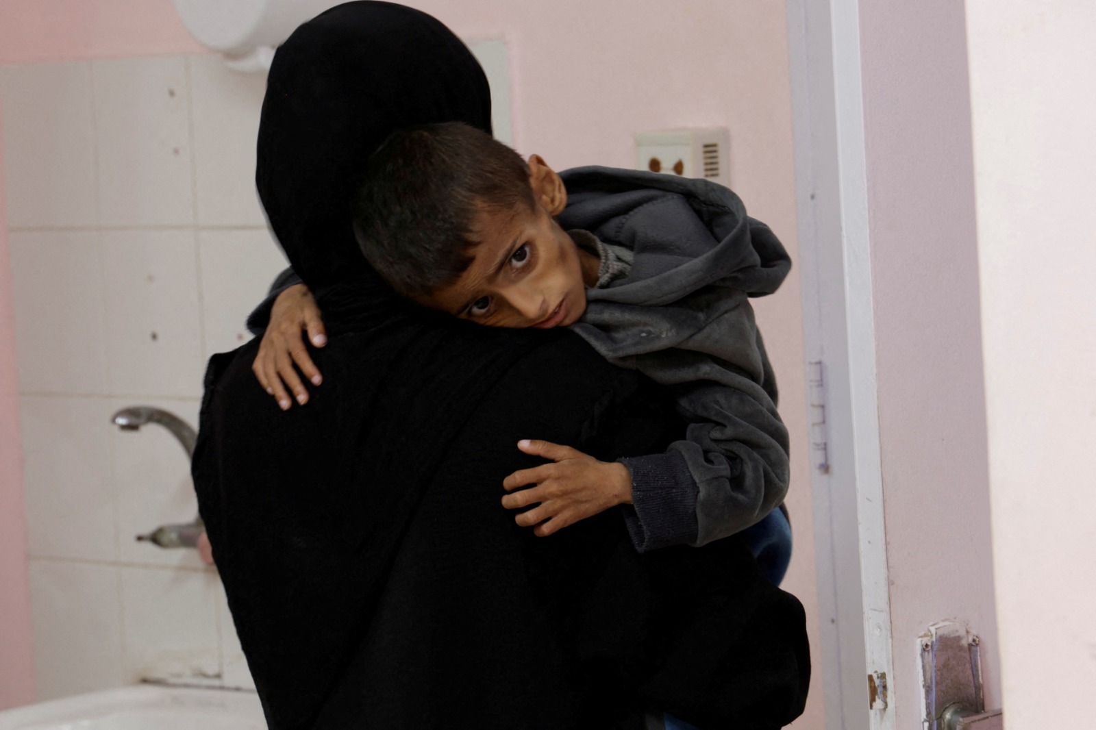 امرأة فلسطينية تحمل طفلاً يعاني من سوء التغذية  في مستشفى ناصر الطبي جنوب قطاع غزة. 30 أبريل 2025