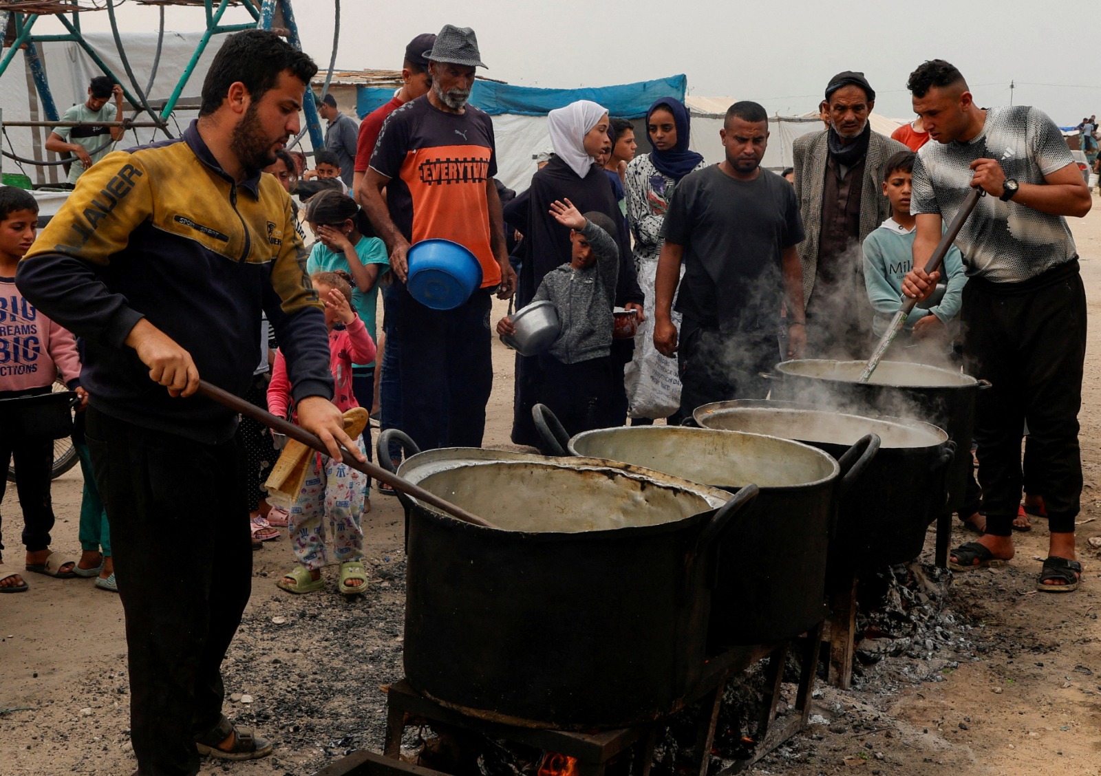 فلسطينيون يتجمعون لتلقي الطعام الذي أعدته جمعية خيرية في خان يونس جنوب قطاع غزة. 8 أبريل 2025