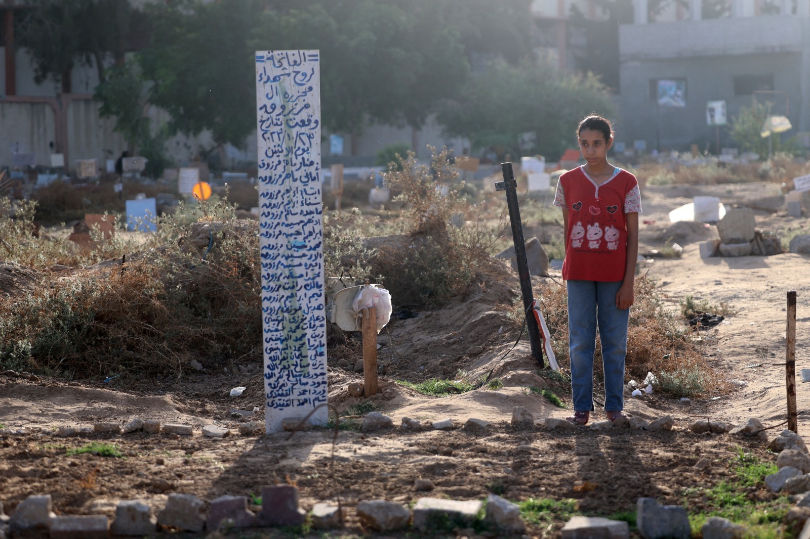 فتاة فلسطينية تزور مقبرة مؤقتة في حي التفاح شرق مدينة غزة. 16 يونيو 2024