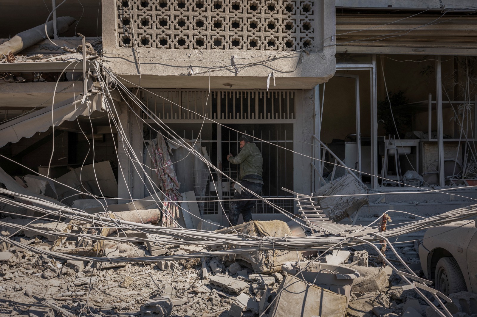 رجل يحاول فتح بوابة مبنى متضرر جراء غارة إسرائيلية على صور، لبنان. 8 أبريل 2026