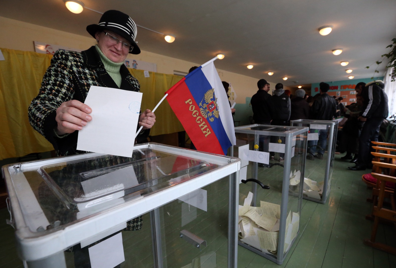 امرأة تحمل العلم الروسي أثناء الإدلاء بصوتها خلال الاستفتاء على وضع منطقة القرم الأوكرانية في مركز اقتراع في مدينة بخشيساراي، 16 مارس 2014