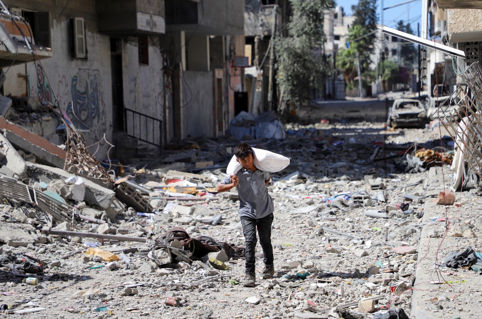 طفل فلسطيني يحمل مساعدات غذائية في حي الصبرة بمدينة غزة بشمال القطاع. 8 أكتوبر 2025