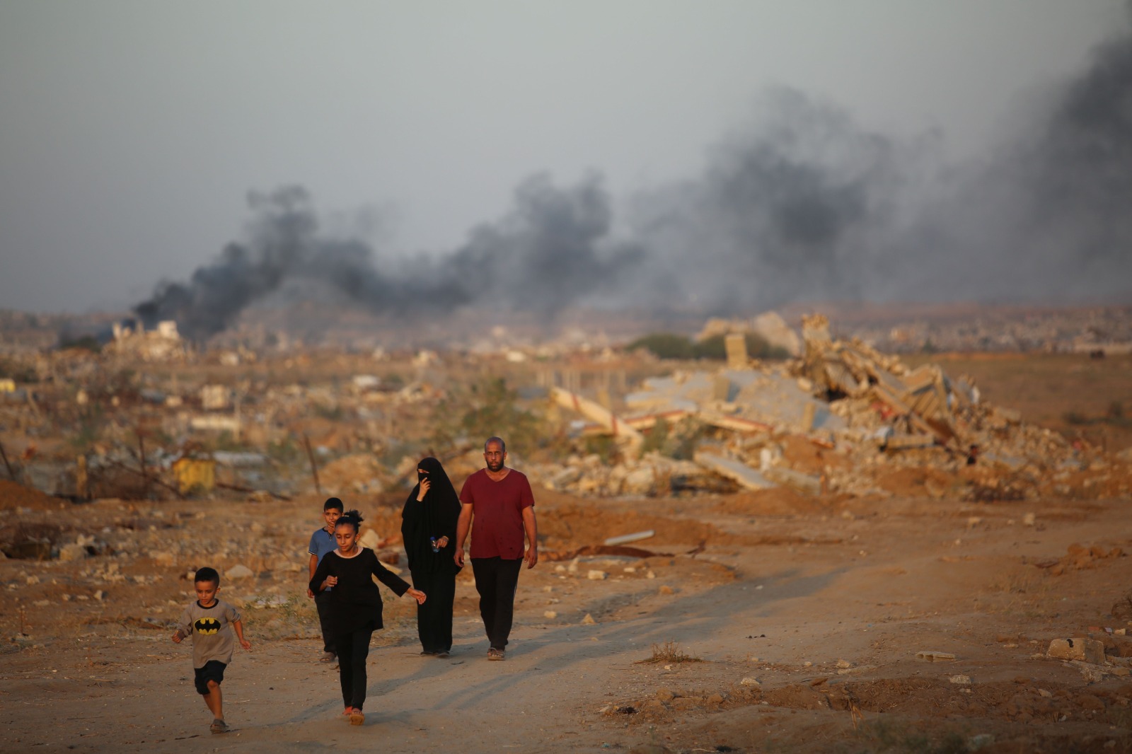 فلسطينيون يسيرون وسط الأنقاض في مخيم النصيرات للاجئين في دير البلح، غزة. 31 أكتوبر 2025