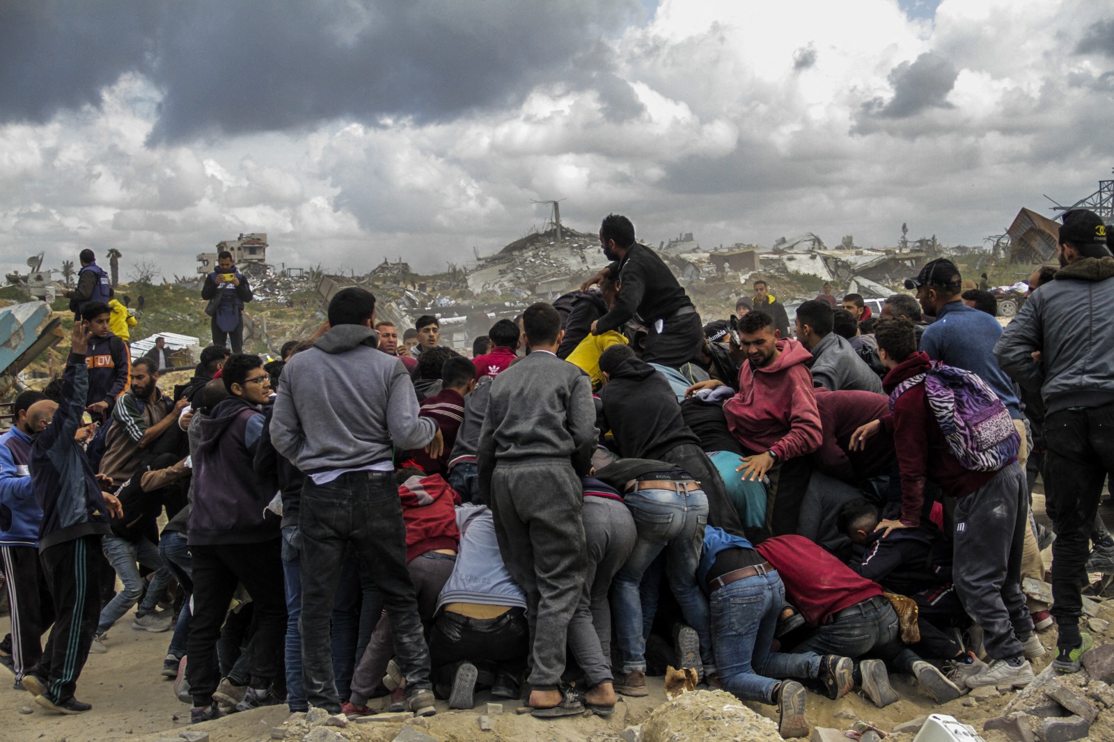 فلسطينيون يتدافعون على شاطئ غزة في محاولة للحصول على المساعدات الغذائية التي يتم إسقاطها عبر الطائرات الحربية على القطاع. 25 مارس 2024