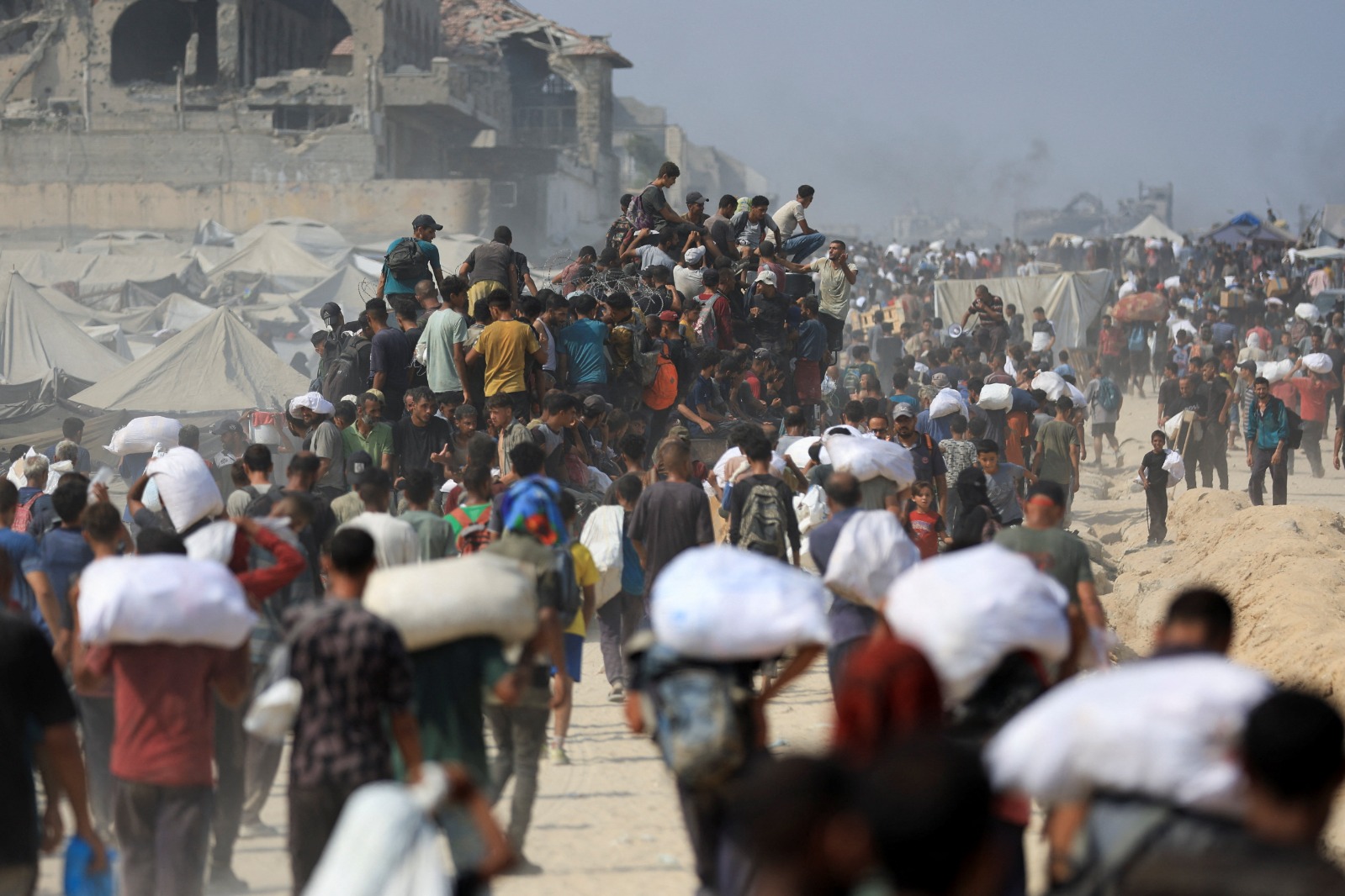 فلسطينيون يحملون مساعدات حصلوا عليها من شاحنات دخلت غزة في بيت لاهيا بشمال قطاع غزة. 10 أغسطس 2025