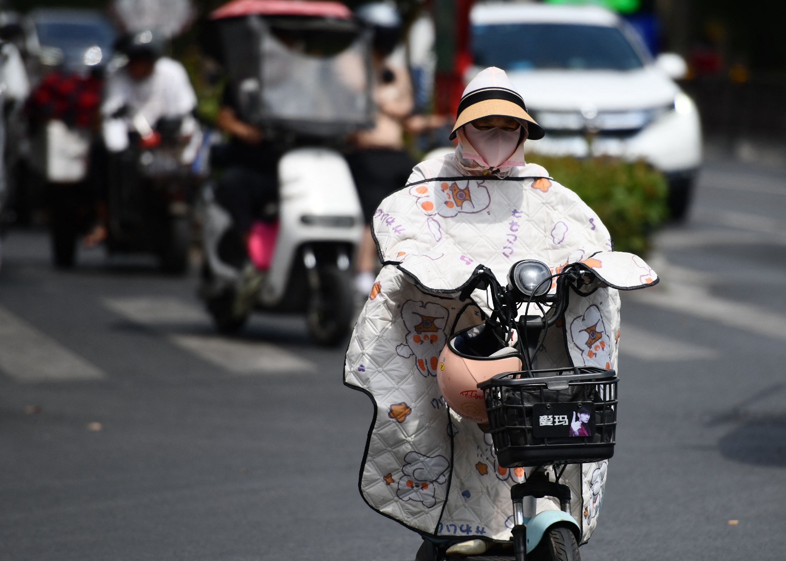 أشخاص يرتدون ملابس واقية من الشمس لحمايتهم من درجات الحرارة المرتفعة بمدينة فويانج في الصين. 11 يونيو 2024