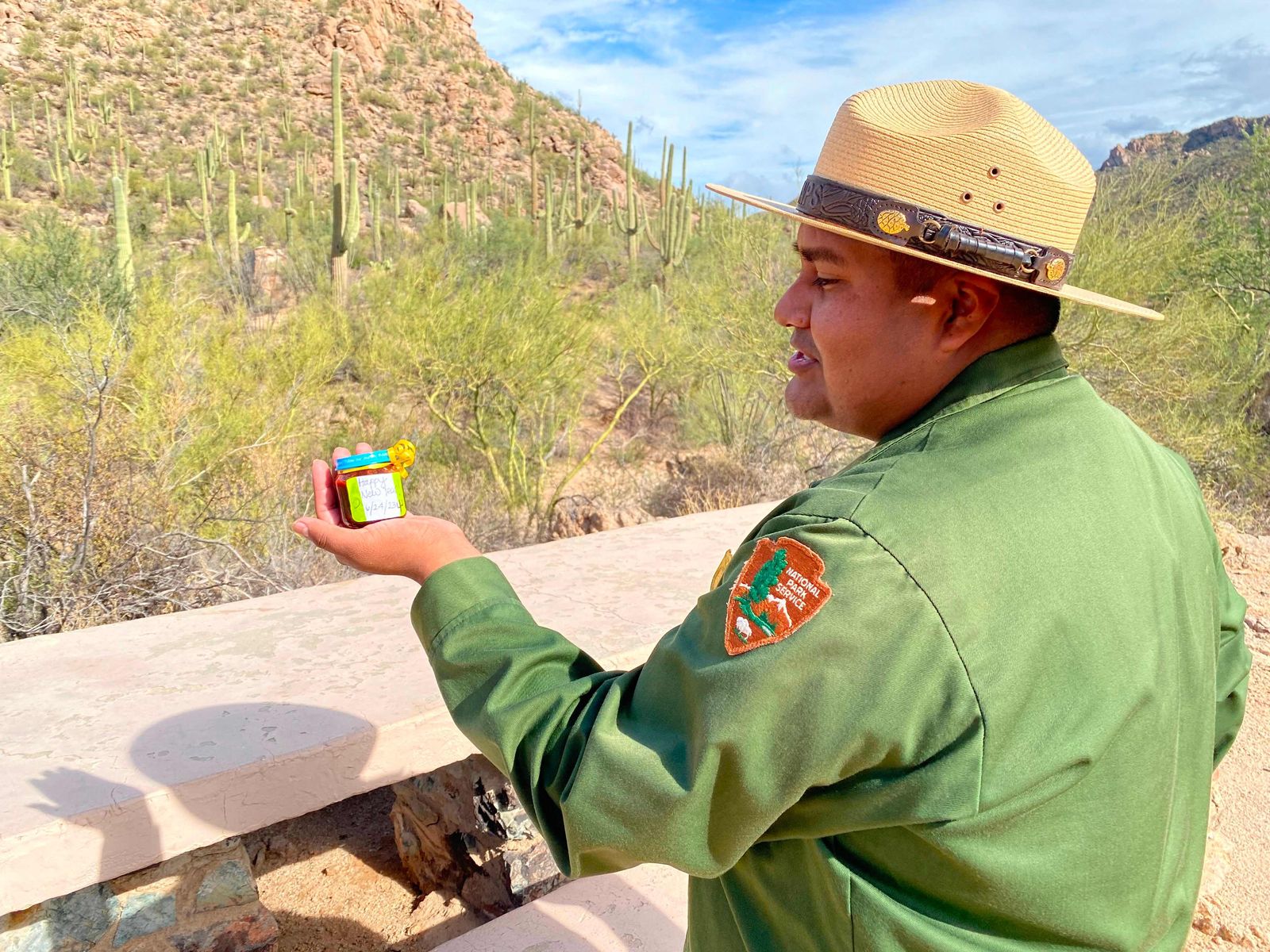 Raeshaun Ramon, ranger at Saguaro National Park, holds syrup from Saguaro fruits on November 17, 2023. Most national parks were set up in areas that are Indigenous ancestral lands. From the 19th century onward, Native Americans were expelled from them or forced to cede them via treaties with unequal terms. When Ramon first donned the distinctive green-and-gray uniform of a US National Park Service ranger, he feared his Native American tribe would judge him for his choice. As a member of the Tohono O'odham Nation, he didn't want to talk too much about his new job at Arizona's Saguaro National Park. 'I was afraid of what my people might think of me,' the 28-year-old confides.'Why work for a place that has done us so much harm in the past?' (Photo by Lucie AUBOURG / AFP)