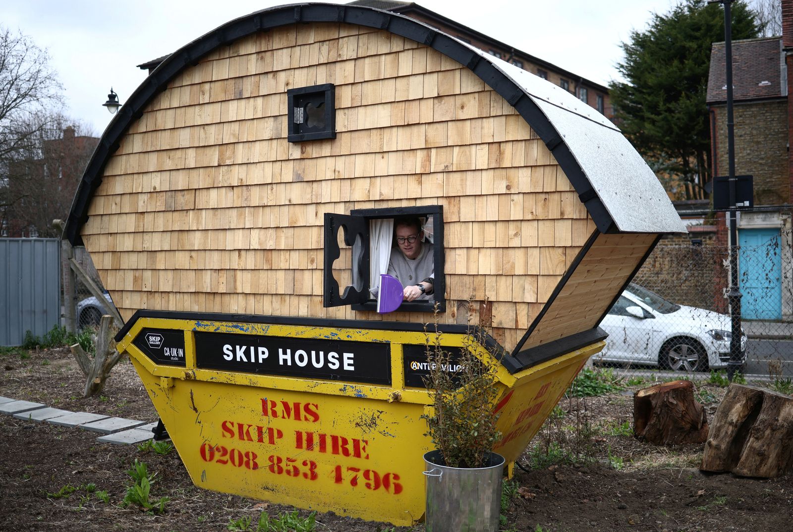 Artist Harrison Marshall who has converted a skip into a home in London - REUTERS