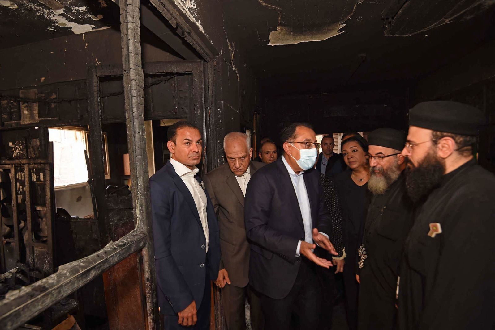 This handout image provided by the office of Egypt's Prime Minister shows Prime Minister Mostafa Madbouli (C) visiting the Abu Sifin Coptic church after a fire broke out during a Sunday service in a working-class district of Greater Cairo on August 14, 2022. - More than 40 people were killed when a blaze, blamed on an electrical fault, hit the Abu Sifin church in densely populated Imbaba west of the Nile river, part of Giza governorate. Witnesses described panicked scenes as people rushed into the multi-storey house of worship to rescue those trapped but were soon overwhelmed by the heat and deadly smoke. (Photo by Egypt's Prime Minister Office / AFP) / RESTRICTED TO EDITORIAL USE - MANDATORY CREDIT 