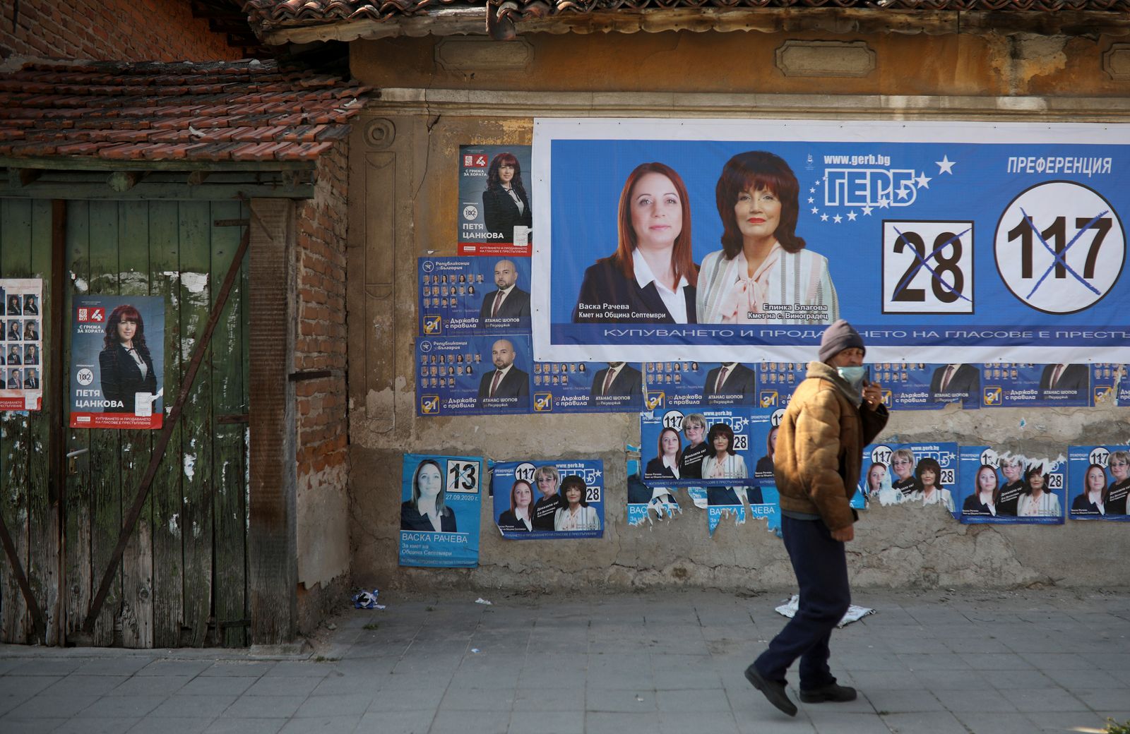 رجل يمشي أمام ملصقات إعلانية انتخابية في قرية فينوغراديتس - 4 أبريل 2021 - REUTERS
