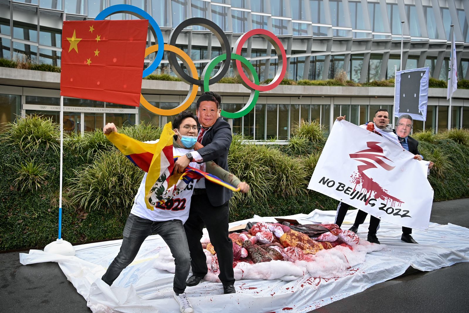 متظاهرون يرتدون أقنعة تحمل الرئيس الصيني ورئيس اللجنة الأولمبية الدولية أمام مقر اللجنة الأولمبية الدولية خلال احتجاج على الألعاب الأولمبية الشتوية في بكين 2022 نظمها نشطاء شبكة التبت الدولية في 3 فبراير 2021 في لوزان - AFP