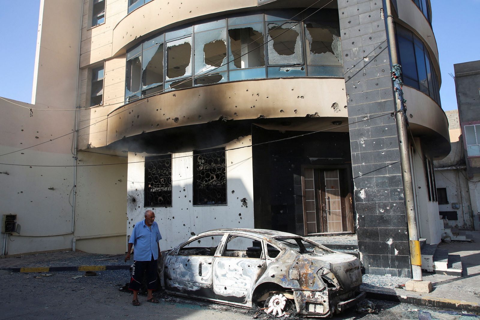 A man looks at a burned car after yesterday's clashes in Tripoli - REUTERS