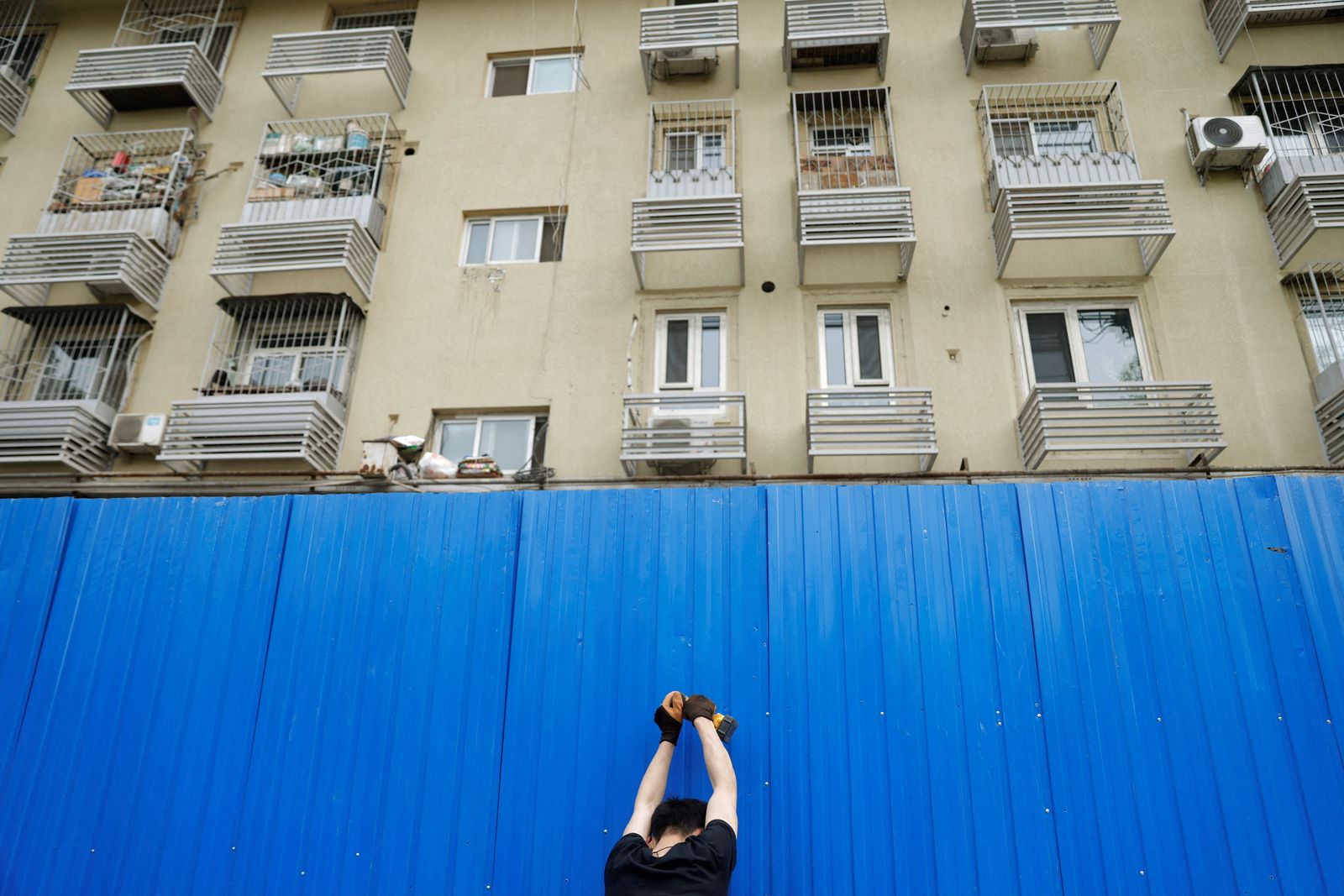 عامل يقيم حاجزاً على بناية تحت الحجر الصحي في العاصمة الصينية بكين. 29 أبريل 2022 - REUTERS