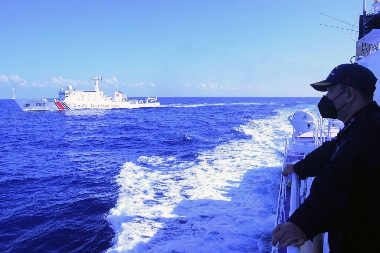 This handout photo taken on March 2, 2022 and released by Philippine Coast Guard (PCG) on March 27, shows a Philippine coast guard personnel (R) monitoring a Chinese coast guard ship shadowing their vessel while conducting a maritime patrol in Scarborough Shoal in South China sea. - The Philippine coastguard accused its Chinese counterpart on March 27 of illegally steering one of its ships close to a Filipino patrol vessel on March 2 in disputed South China Sea waters, risking a collision. (Photo by Handout / Philippine Coast Guard (PCG) / AFP) / RESTRICTED TO EDITORIAL USE - MANDATORY CREDIT 