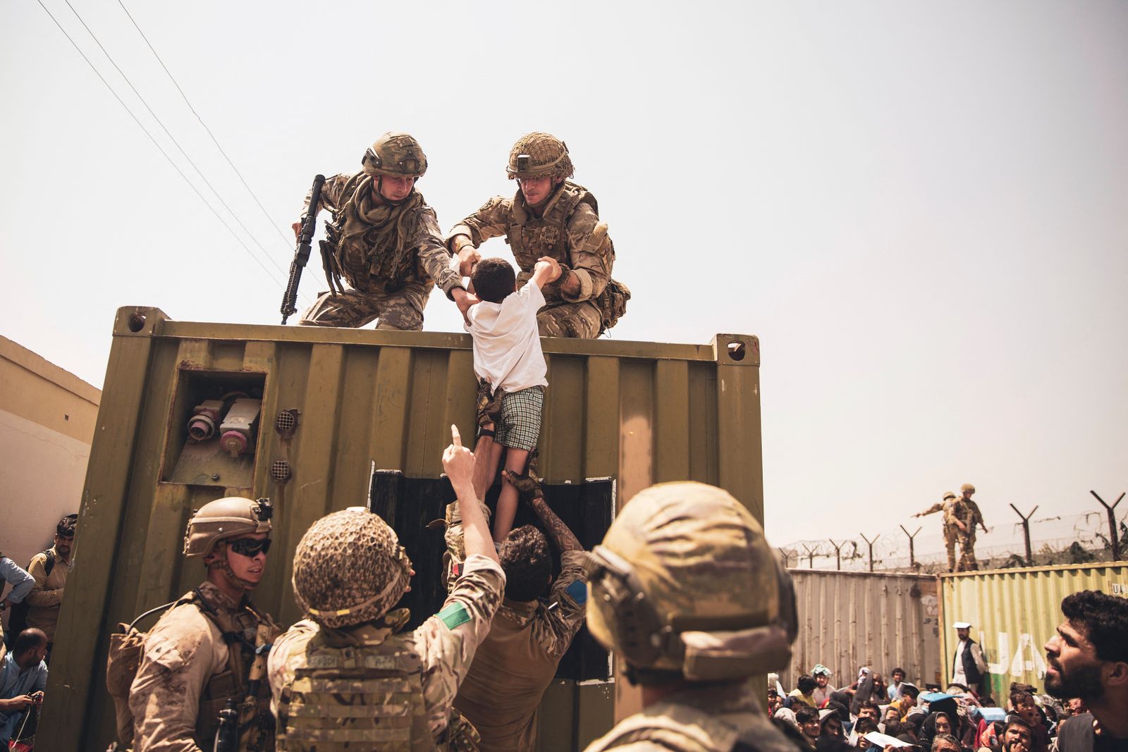 قوات التحالف البريطانية والتركية ومشاة البحرية الأميركية تساعد طفلاً خلال عملية إجلاء في مطار حامد كرزاي الدولي في كابول - 20 أغسطس 2021 - AFP