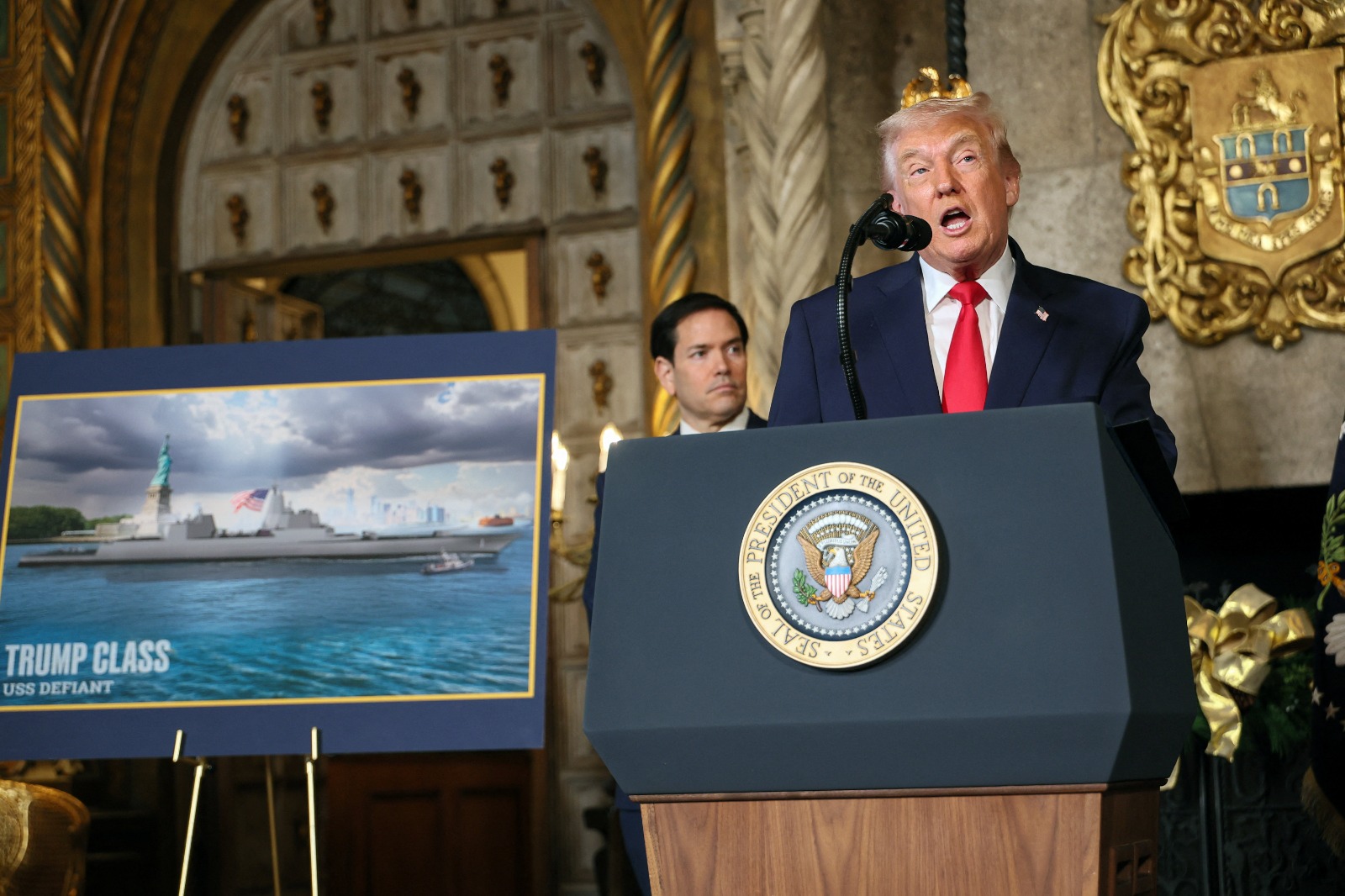 الرئيس الأميركي دونالد ترمب خلال الإعلان عن 'الأسطول الذهبي' التابع للبحرية الأميركية، وبجواره صورة لمخطط سفينة 'ترمب' الحربية، في فلوريدا، الولايات المتحدة، 22 ديسمبر 2025.