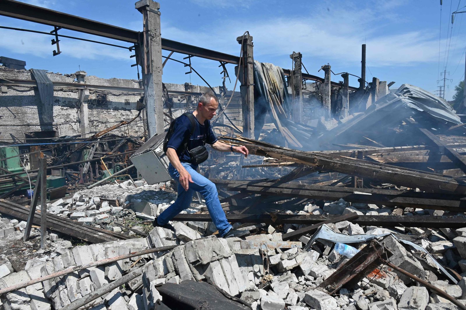 A man walks through the rubble of destroyed building at Mashgidroprivod plant, after a Russian missile attack in Kharkiv on June 29, 2022 amid the Russian invasion of Ukraine. - The plant produces parts for agricultural machinery and machines for public utilities. (Photo by SERGEY BOBOK / AFP) - AFP