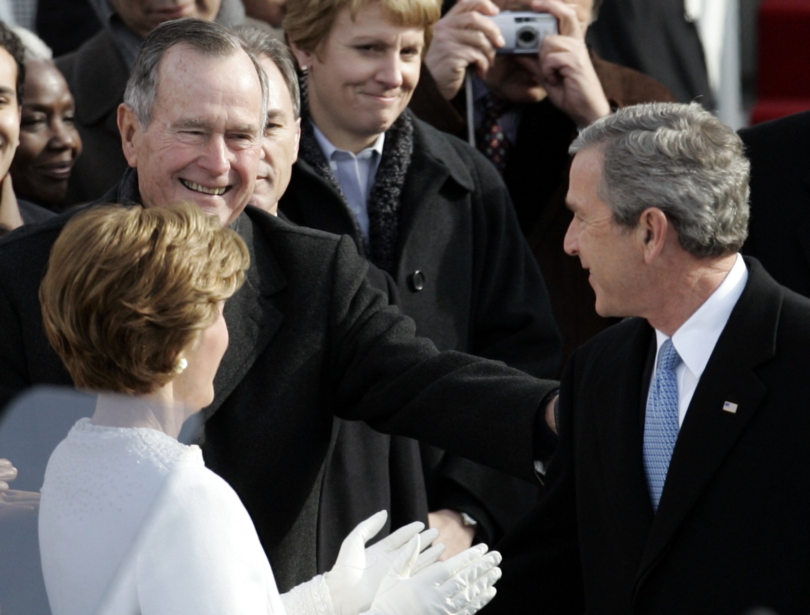 الرئيس الأميركي السابق جورج بوش الأب من الخلف إلى اليسار يهنئ ابنه الرئيس الأميريكي السابق جورج دبليو. بوش بعد أن أدى اليمين الدستورية في الكابيتول هيل في واشنطن. 20 يناير 2005