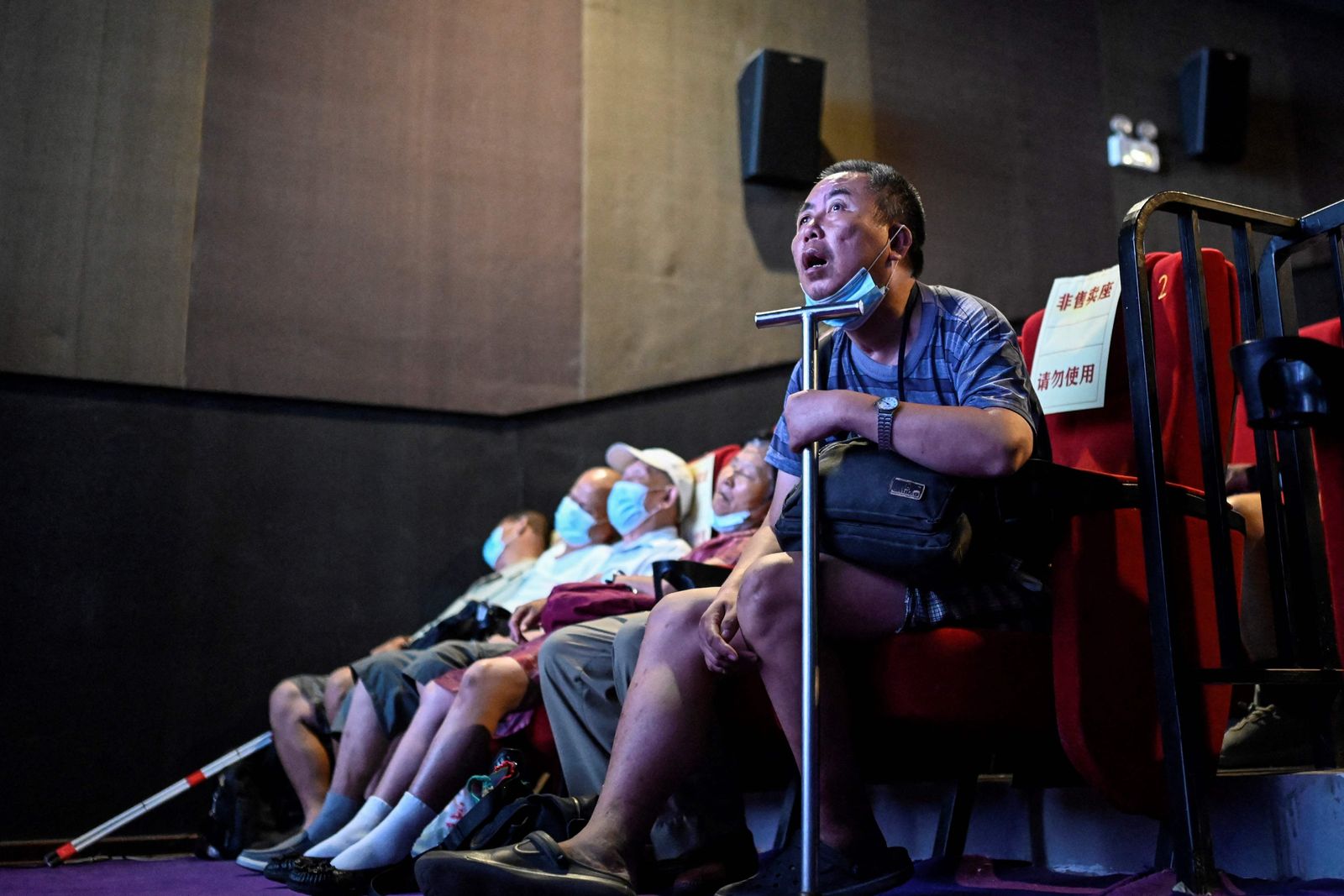 This photo taken on August 7, 2021 shows visually impaired people listening to the film narrator during a screening at a cinema in Beijing. - Dozens of blind moviegoers come to the Saturday screenings organised by Xin Mu Theater, a small group of volunteers who were the first to introduce films to blind audiences in China. (Photo by Jade GAO / AFP) / To go with AFP story China-social-disabled-film, FEATURE by Poornima WEERASEKARA and Danni ZHU - AFP