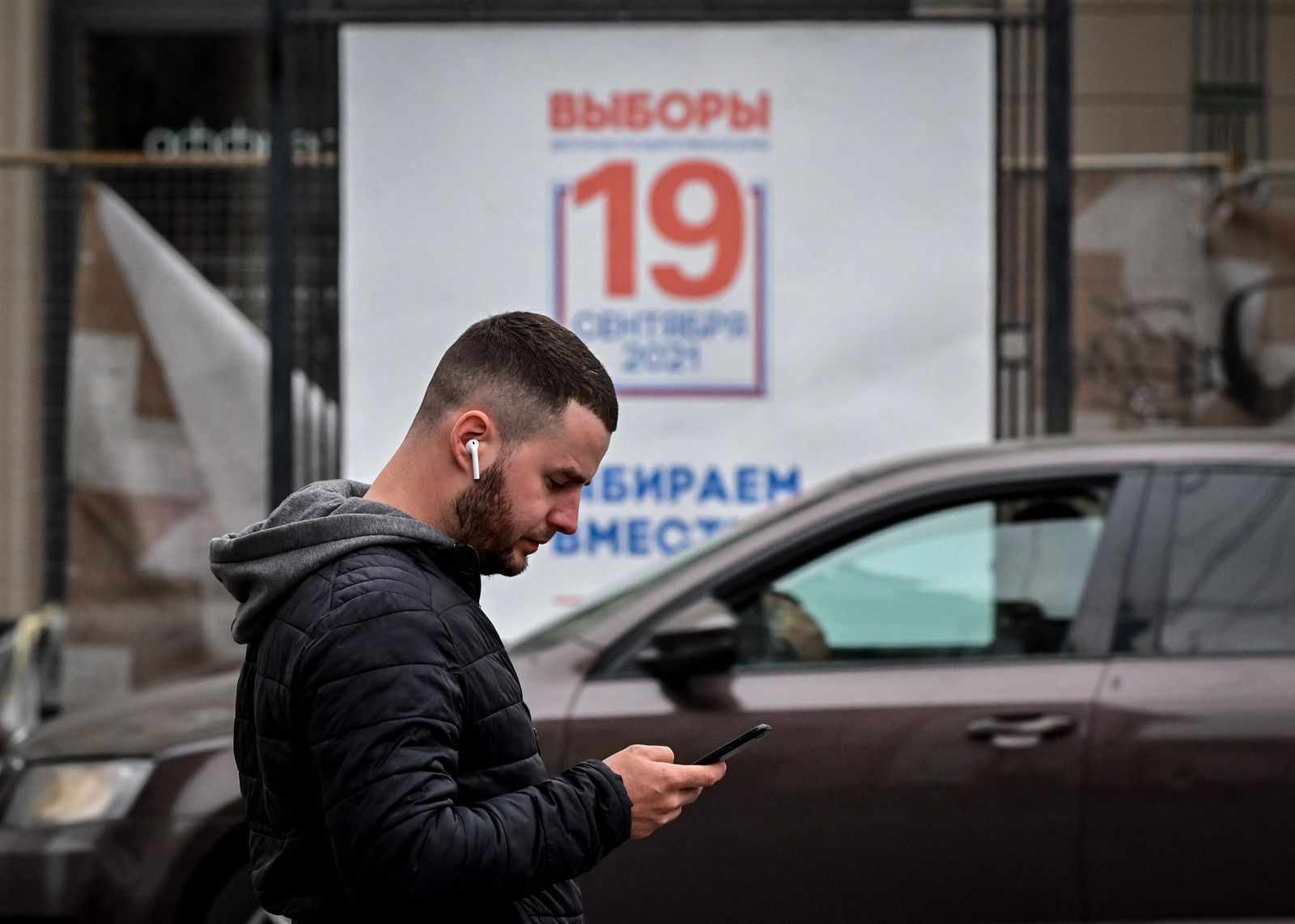 A man uses his smartphone walking past a poster announcing the upcoming election to the Russian State Duma, the lower chamber of Russia's parliament, in Moscow on September 14, 2021. (Photo by Yuri KADOBNOV / AFP) - AFP