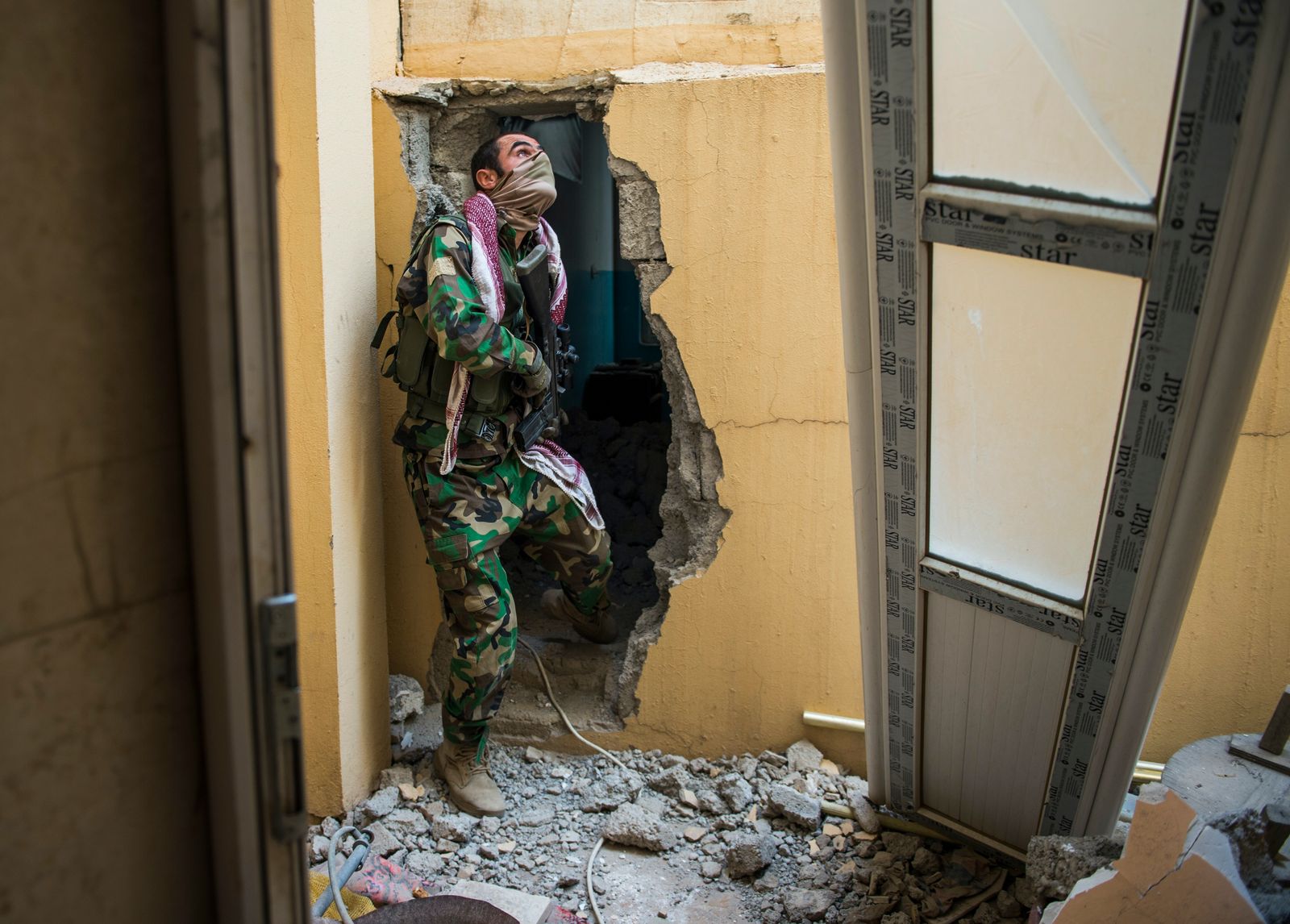 مقاتل من البشمركة يبحث عن عناصر من داعش بينما يتنقل هو وفريقه بين المباني في بعشيقة بالموصل - 9 نوفمبر 2016 - AFP